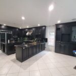 Glossy black modern cabinetry in stark white kitchen