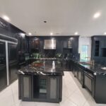 Black cabinetry, dark marble countertop in new kitchen