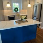 White marble countertops with white cabinet and stainless steel fixtures and appliances and a royal blue cabineted island in modern kitchen by LaClave Home Improvements