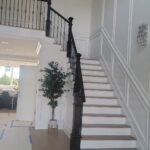 Grandiose white staircase with white Wainscoting black banister and light wooden steps