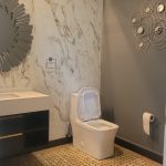 Warm and eclectic modern bathroom with Mosaic floor tiling, seamless marble backsplash, floating modern vanity and warm grey accent wall - wall tile installation