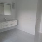 Modern white and bright bathroom with floating bathroom vanity, seamless white tile floor and chrome fixtures