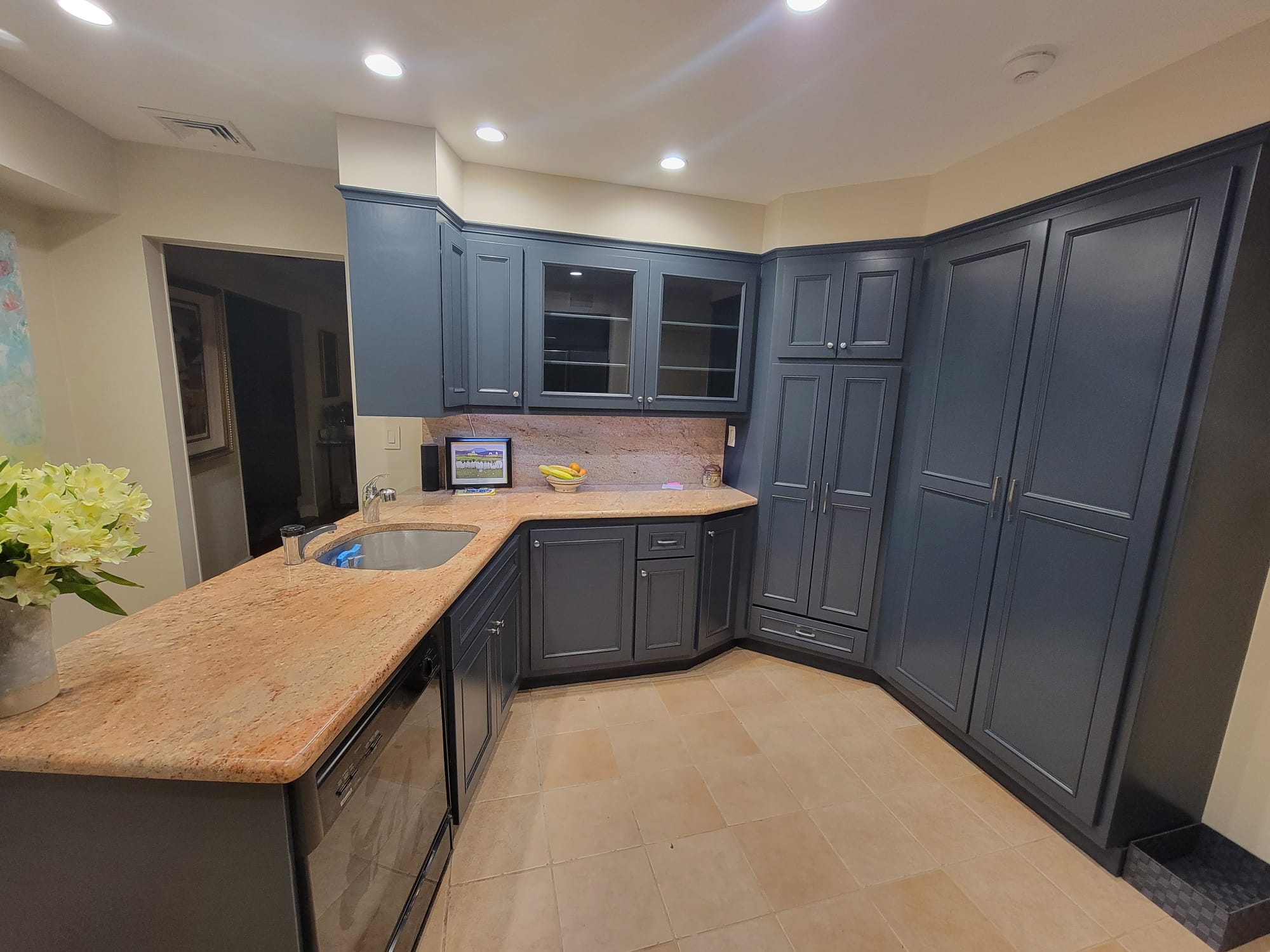 Refrigerator and appliances enclosed in custom modern cabinetry with bright countertops and stainless steel fixtures